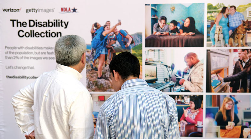 Two people looking at a large collage of photos from The Disability Collection.