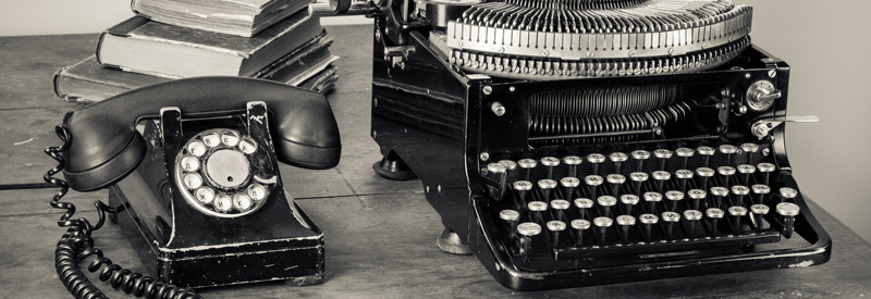 An old phone and an old typewriter on a desk