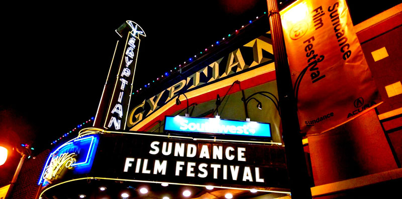 A brightly-colored well-lit marquee outside a movie theatre reads Sundance Film Festival.